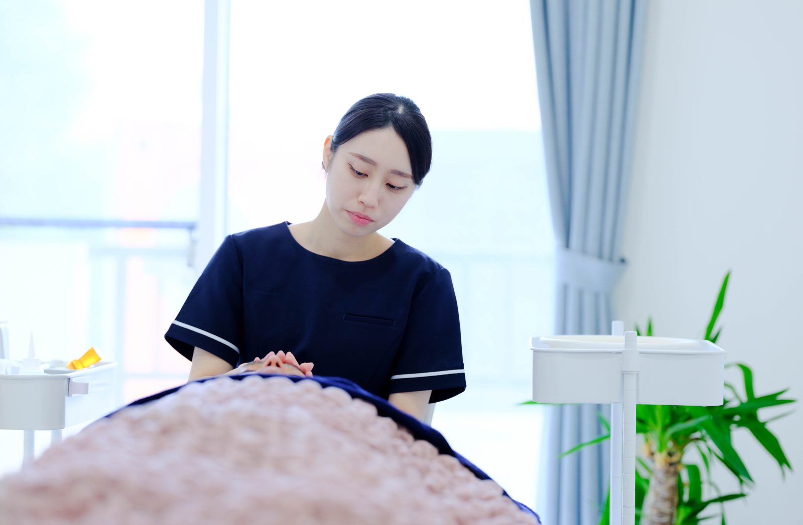 ベッドの頭側で手元を見つめる高橋桃花